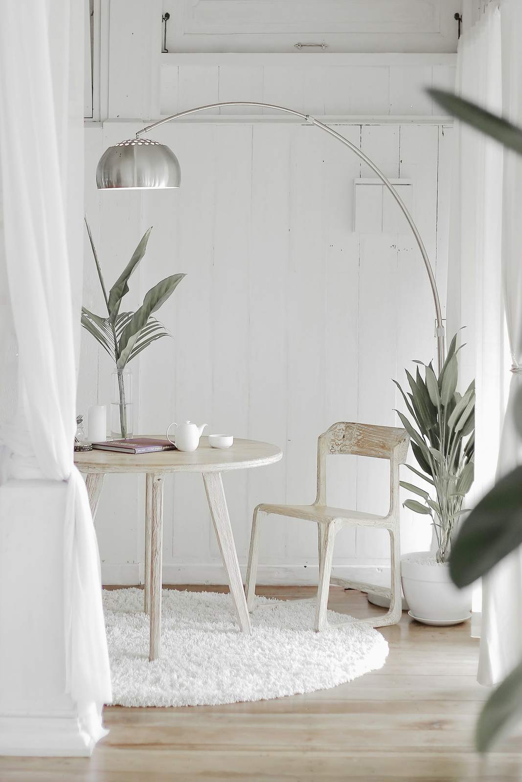 White reading nook with a small table and plants